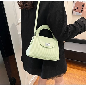Detail of mint green pleated handbag with silver twist lock and slim shoulder strap