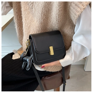Detail of black crossbody bag featuring a gold lock and cute dachshund dog charm