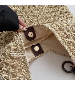 Detail of magnetic snap closure and beige fabric lining on woven straw tote bag