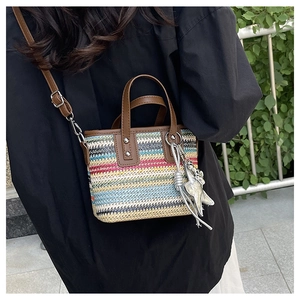 Detail of colorful striped woven beach bag featuring brown leather handles and starfish charm