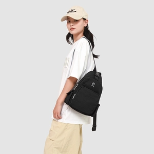 Detail of a black canvas crossbody chest bag featuring adjustable wide fabric straps and buckles