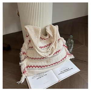 Detail of cream knitted tote bag featuring bohemian tassels and red geometric texture