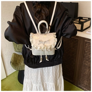 Back view of a white mini lace backpack with ruffles, bow, and pearl details on model