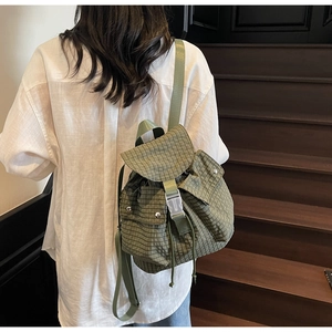 Detail eines grünen Karorucksacks mit Schnallenklappe und Seitentaschen am Modell