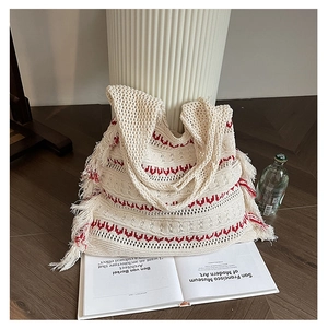 Detailed close-up of bohemian knitted tote bag with red wave patterns and fringe accents