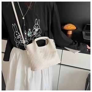 Detailed close-up of a white woven handbag featuring premium texture and sleek handle design