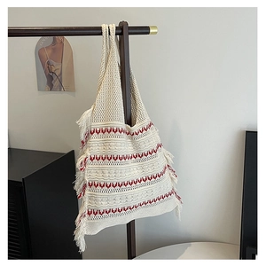 Detail of knitted tote bag showing geometric red patterns and side tassel accents