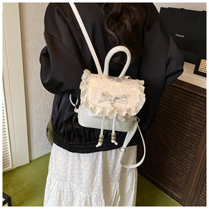 Detailed back view of a white lace-trimmed backpack with bow and pearl charms on a model