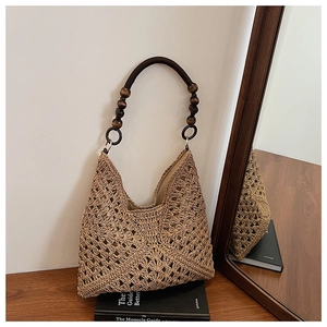 Detail of hollow-out straw woven tote bag with vintage dark wooden beaded handle