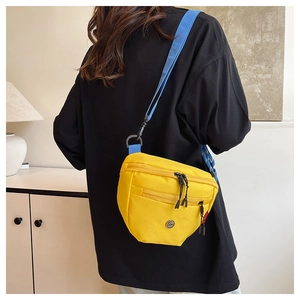 Dettaglio di un marsupio in tela giallo brillante con tracolla blu e logo in metallo