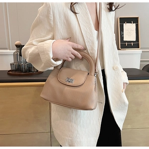 Detail of light khaki pleated handbag featuring a silver twist lock and smooth leather flap