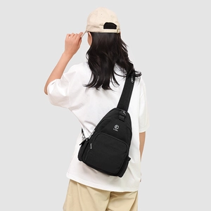 Detail of a black canvas multi-pocket crossbody chest bag with adjustable strap and logo
