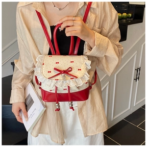 Detailed view of red and white lace backpack with bow and beige polka dot fabric