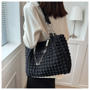 Detail of black bubble texture tote bag with pearl flower chain and leather fashion label