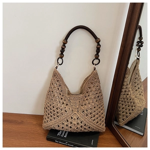 Detailed close-up of woven straw tote bag with decorative dark wooden bead handle
