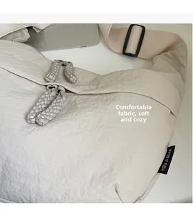 Detailed close-up of soft wrinkled nylon fabric and woven zipper puller on beige bag