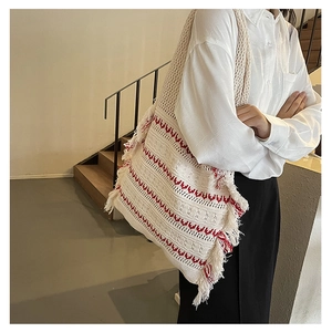 Detail of bohemian knit tote bag showing white and red woven patterns and long fringe