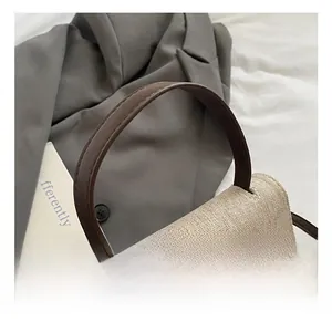 Gros plan sur la texture tissée beige et la poignée en cuir marron du sac à main