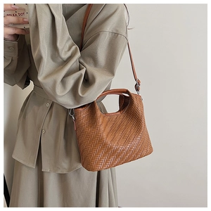 Detail of caramel woven leather bucket bag texture and silver metal hardware