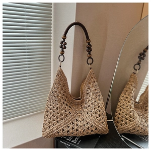 Detail of woven straw tote bag featuring decorative dark wood beads on handle straps