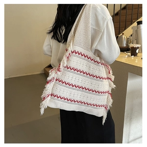 Close-up of white knit tote bag featuring red wavy patterns and bohemian fringe details