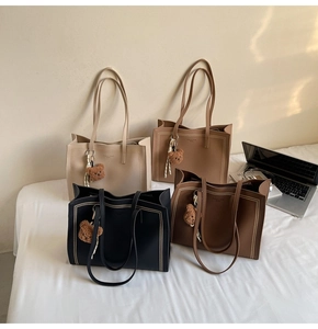 Detail of four large tote bags in beige, khaki, brown, and black with cute bear charms