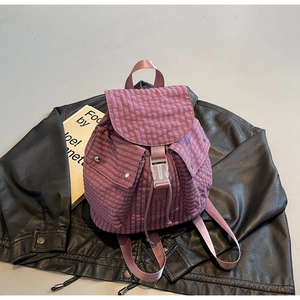 Detailansicht lila karierter Rucksack mit Kordelzug und Schnalle auf einer Lederjacke
