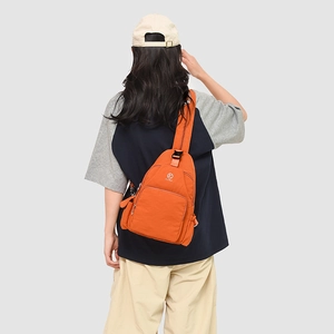 Detail showing an orange cross-body chest bag with adjustable strap on female model