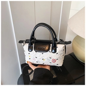 Dettaglio di una borsa chic a contrasto bianco e nero con graziose ricami di cartoni