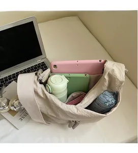 Spacious interior of beige crossbody dumpling bag showing storage for laptop and essentials