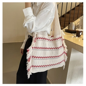 Detail of bohemian knit tote bag with red wave patterns and fringe trim on the shoulder