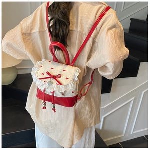 Mini backpack in red and white with lace trim and bow detail shown on a model