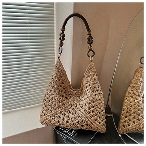 Detailed close-up of hand-woven straw tote with vintage dark brown wooden bead straps