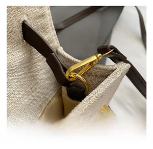 Détails des crochets dorés sur un sac en toile beige avec bordure en cuir marron