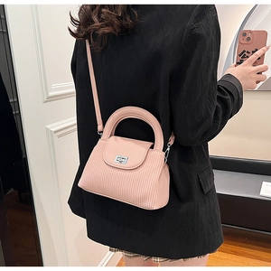 Pink PU leather crossbody bag with pleated texture and silver twist lock on a model