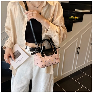 Mini borsa rosa a pieghe con ricamo a cuore e manici in pelle nera indossata dalla modella