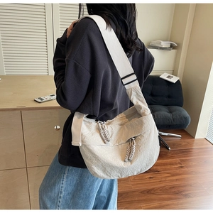Detail of minimalist cream crossbody bag featuring crinkled texture fabric and woven zipper pull