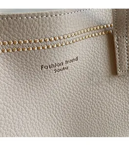 Detailed close-up of beige lychee grain leather with woven decor and brand logo