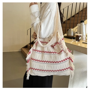Close-up of a woven knit tote bag with red wave patterns and stylish side fringe details