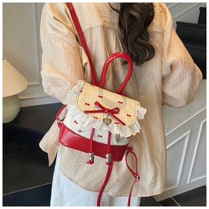 Detail view of red lace backpack featuring bowknots and a heart charm in balletcore style