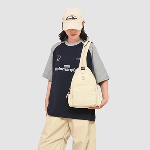 Detail of beige canvas crossbody sling bag showing front zipper and washed texture