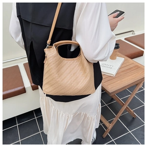 Detail of light brown woven handbag featuring a fine V-pattern and adjustable leather strap
