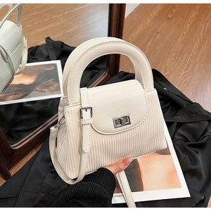 Detail of cream crossbody bag featuring vertical pleats and silver twist lock closure