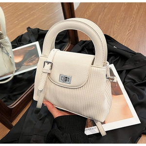 Close-up of cream pleated shoulder bag with vertical texture and silver metal twist lock