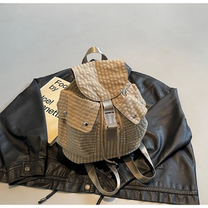 Detail eines karierten Canvas-Rucksacks mit Kordelzug und vorderen Klappentaschen