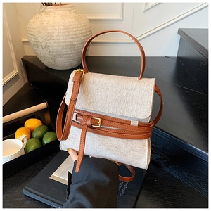 Détail du sac en toile avec lanière en cuir marron et boucle dans un décor chic
