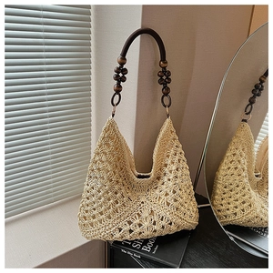 Detailed shot of straw tote bag with brown wooden bead straps and hollow crochet pattern