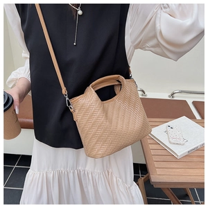 Close-up of woven texture khaki tote bag with top handle and strap in cafe setting