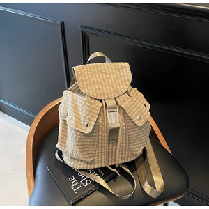 Detailansicht des karierten Rucksacks mit Klappe, Schnalle und Taschen mit Metalldruckknopf
