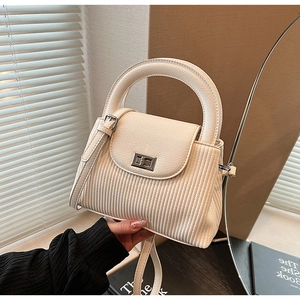 Close-up of pleated cream handbag showing silver turn-lock and vintage vertical texture